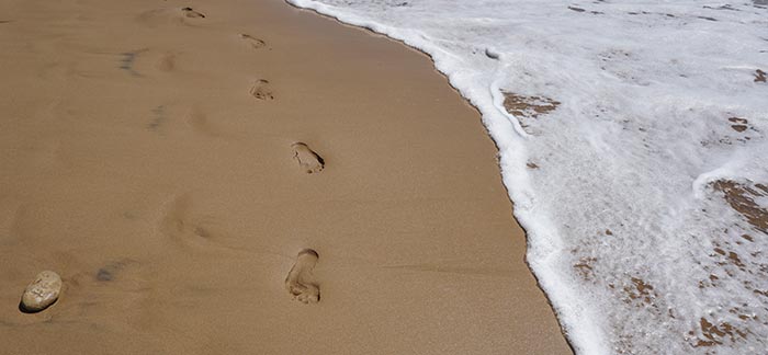 footprints in the sand on the beach for Quotacy blog Easy Ways to Reduce your Carbon footprint