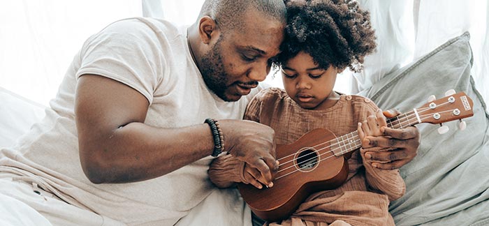 dad with daughter teaching her guitar for Quotacy blog 5 Tips to Teach Your Kids to Deal With Uncertainty