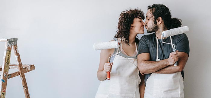 couple kissing while painting a room for Quotacy blog laddering life insurance to save money.