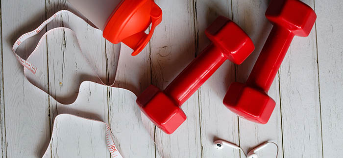 set of red free weights, tape measurer, and water bottle for Quotacy blog life insurance after weight loss surgery