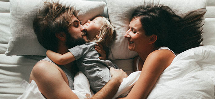 parents cuddling with child for Quotacy blog working parents need life insurance