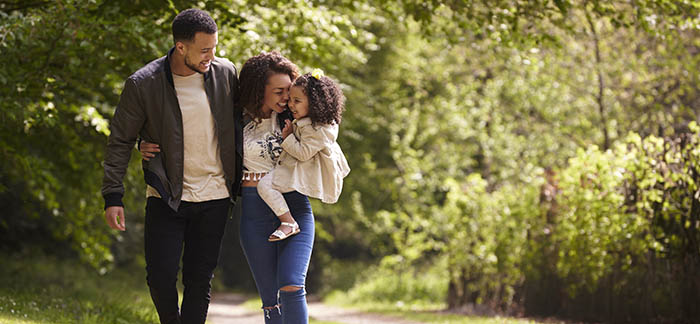 mixed mom, dad, and child walking in woods for Quotacy blog financial protection for family with life insurance