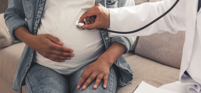 Black pregnant woman with doctor for Quotacy blog gestational diabetes and life insurance