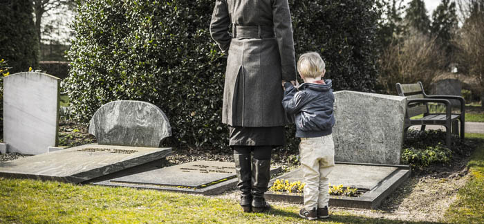 mother standing at grave with her son grieving