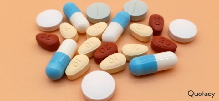 a small collection of various types of pills on a light orange background