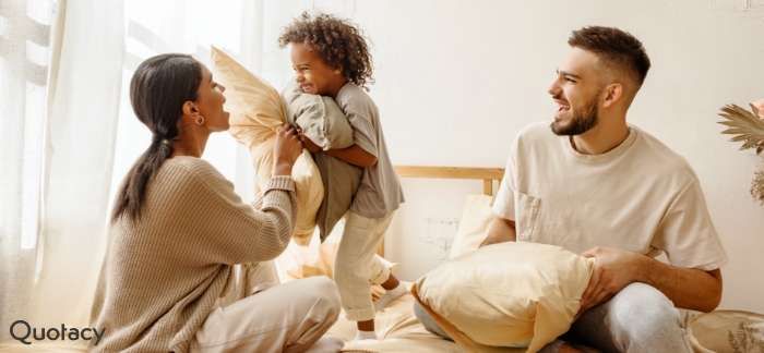 parents and their small child having a playful pillow fight