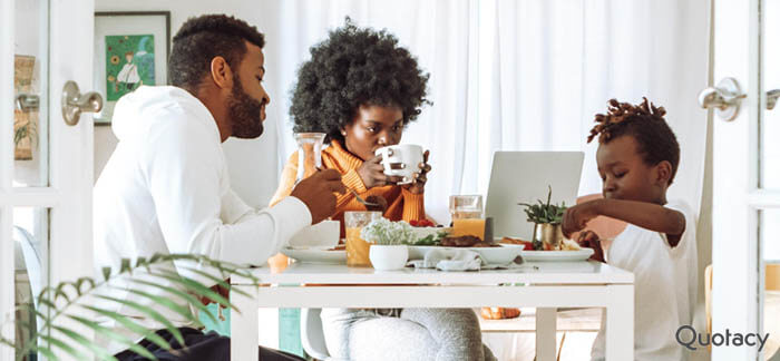 Family sitting around the breakfast table looking at the computer